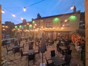 un patio avec des tables et des chaises en face d'un bâtiment dans l'établissement The Stump Cross inn, à Halifax