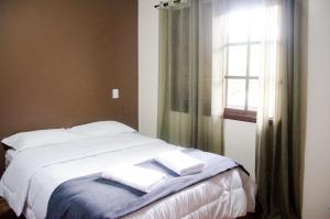 1 dormitorio con 1 cama con 2 toallas en Residenciais Belo Centro Gramado, en Gramado