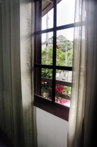 a window with a view of a garden with flowers at Residenciais Belo Centro Gramado in Gramado