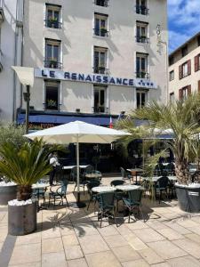 a patio with tables and chairs and a building at Le Renaissance in Aurillac