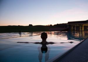 a woman in a swimming pool in the water at Haubers Naturresort Landhaus in Oberstaufen