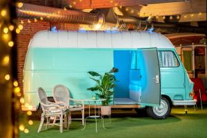 Outside Inn في أمستردام: سيارة فان زرقاء وبيضاء مع طاولة وكراسي