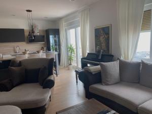 a living room with two couches and a kitchen at Linden Trsat with balcony in Rijeka