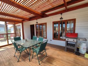 een patio met een tafel en stoelen en een grill bij Amplia y acogedora Casa, a 10 min de playa en auto in Los Molles