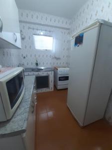 a kitchen with a white refrigerator and a microwave at Apartamento FRENTE MAR - Vista Lateral - PRAIA GRANDE in Solemar