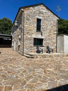 a stone building with two benches in front of it at Pensión Xacobe in Cabreiros