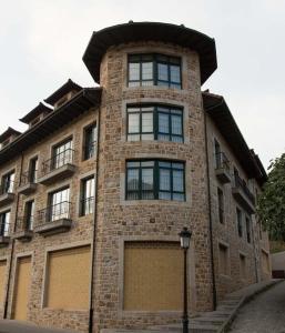 a tall brick building with windows and a street light at Apartamentos Villa de Cabrales in Arenas de Cabrales
