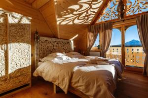 a bedroom with a large bed in a room with windows at Bajkowa LUX Magiczne Domki z Jacuzzi in Murzasichle +65 photos