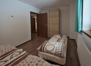 two beds in a room with wooden floors at Apartmany Maliarik in Demanovska Dolina