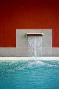 einem Brunnen vor einer roten Wand in der Unterkunft Il Porticciolo in Laveno-Mombello