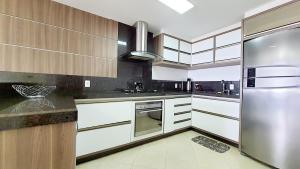 a kitchen with white cabinets and a stainless steel refrigerator at Residencial Yasmin - Apto 3 dormitorios vista mar Praia de Palmas in Governador Celso Ramos +6 photos
