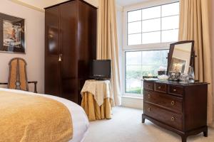 a bedroom with a bed and a dresser and a window at Ees Wyke Country House in Near Sawrey