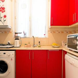 a kitchen with red cabinets and a washing machine at Best location in İstanbul in Istanbul