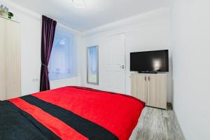 - une chambre avec un lit rouge et une télévision à écran plat dans l'établissement Studio Central Poarta Schei, à Braşov