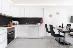 a kitchen with white cabinets and a table with chairs at Manuda Luxury Apartment in Caleta De Fuste