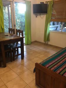 uma sala de jantar com uma mesa e cortinas verdes em Cabañas La Viña em Chascomús
