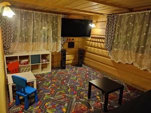 Pokój z telewizorem, stołem i niebieskim krzesłem w obiekcie Tatrzańskie Kwatery w Bukowinie Tatrzańskiej