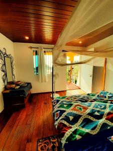 a bedroom with a bed and a wooden floor at La Rocha in Patnem
