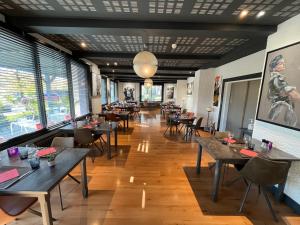 una sala da pranzo con tavoli, sedie e finestre di Hôtel Logis Restaurant La Fontaine a Mantry
