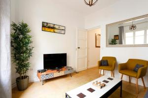 - un salon avec une télévision, une table et des chaises dans l'établissement Bonito Apartamento a un paso del centro., à Séville