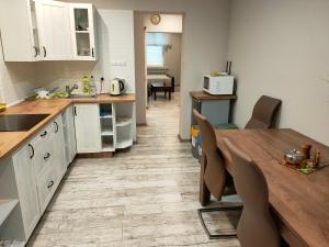 a kitchen with white cabinets and a wooden table with chairs at Wałcz nad jeziorem in Wałcz +7 photos