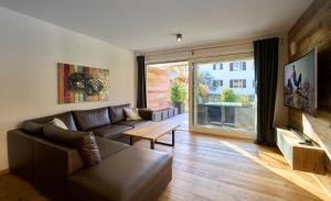 a living room with a leather couch and a large window at Chalet Alpenspirit in Garmisch-Partenkirchen