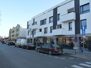 a street with cars parked in front of a building at Apartament w centrum Ciechocinka in Ciechocinek