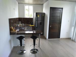 eine Küche mit einem Kühlschrank und einer Theke mit Stühlen in der Unterkunft Aparta-Hotel LENEMBERGER in Puerto Asís
