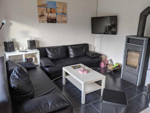 a living room with a black couch and a fireplace at Ferienhaus Sander in Friedrichskoog-Spitz