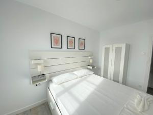 a white bedroom with a bed and two pictures on the wall at Benlloch Silence in Valencia