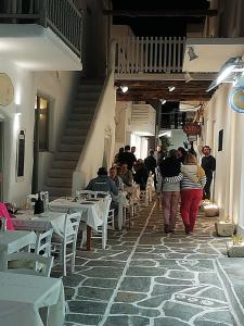 a group of people walking through a restaurant with tables and chairs at Sunloft-Paros in Naousa