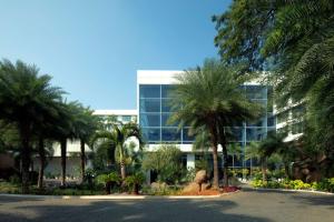 ein großes Glasgebäude mit Palmen davor in der Unterkunft Radisson Blu Plaza Hotel Hyderabad Banjara Hills in Hyderabad
