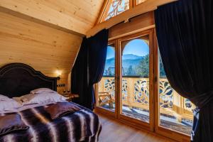 a bedroom with a bed and a large window at Bajkowa Chata 3 Magiczne Domki Jacuzzi in Murzasichle