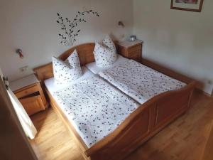 - une chambre avec un grand lit en bois et des oreillers dans l'établissement Ferienwohnung Baumgart, à Schönau am Königssee