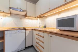 una cocina con armarios blancos y TV en una encimera en Monte Cervino apartment AS1, en Breuil-Cervinia