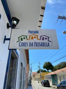 a sign hanging off the side of a building at Pousada Cores da Passarela - Sob nova direção in Porto Seguro