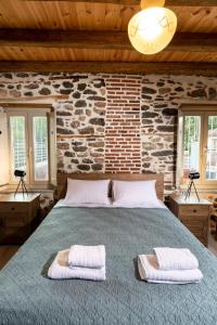 StoneVillaMouzaki Luxury Mansion في موزاكيون: غرفة نوم بها سرير كبير عليه منشفتين