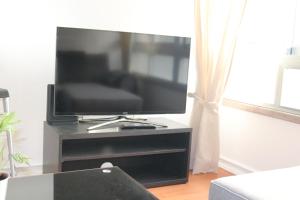 TV de pantalla plana en un centro de entretenimiento negro en Chez Jacqueline en Lisboa