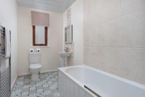 a bathroom with a tub and a toilet and a sink at Prestwick Central - Donnini Apartments in Prestwick