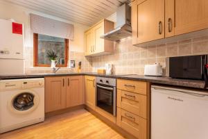 a kitchen with wooden cabinets and a washer and dryer at Prestwick Central - Donnini Apartments in Prestwick