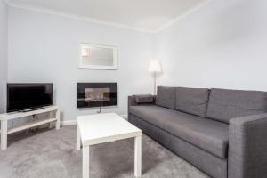 a living room with a gray couch and a tv at Prestwick Central - Donnini Apartments in Prestwick