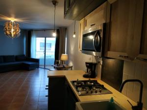 a kitchen with a stove top oven next to a living room at Modern, Welcoming Studio, Ocean View in Juan Dolio in Juan Dolio