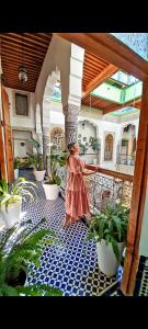 a woman standing on a patio with potted plants at Riad Fes Nass Zmane in Fez
