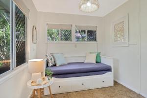 Bett in einem Zimmer mit Fenstern und einer lila Decke in der Unterkunft 16 Bigoon Road in Point Lookout