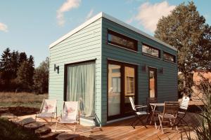 a green tiny house with a table and chairs at TINYLODGE am Ellertshäuser See in Stadtlauringen