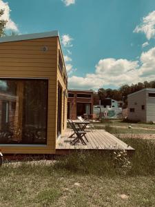 a tiny house with a picnic table on a deck at TINYLODGE am Ellertshäuser See in Stadtlauringen