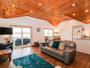 - un salon avec un canapé en cuir et des plafonds en bois dans l'établissement Teal Lodge, à Tattershall
