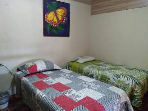 two beds in a room with a quilt on the wall at CreaDora in Boquete