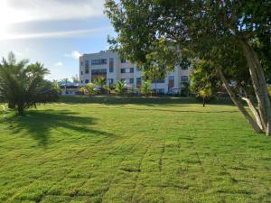 a large grassy field in front of a building at Flat Cantinho do Paraíso in Guarajuba