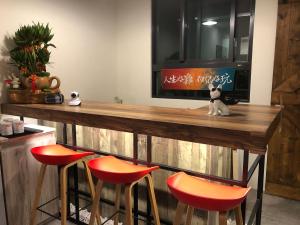 a bar with orange stools and a television on a wall at 樸宿民宿 in Guanshan